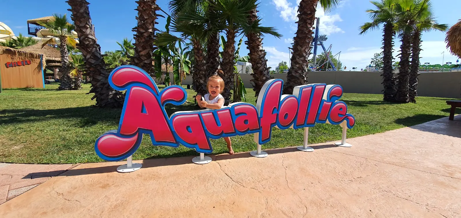 Una bambina sorride dietro al logo instagrammabile di Aquafollie.