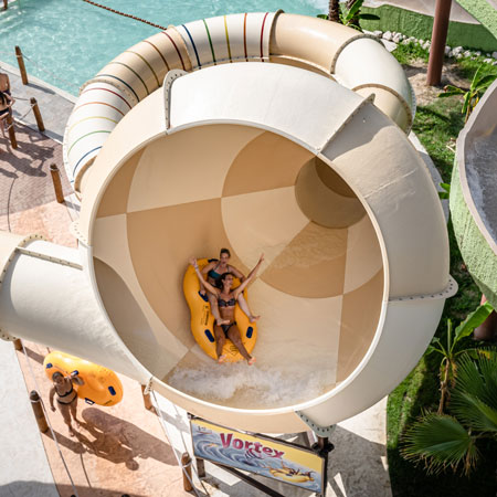 Due persone scivolano insieme su Vortex nel parco acquatico di Caorle.
